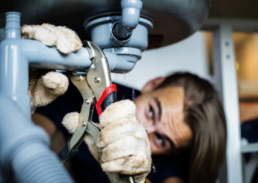 plumber fixing the plumbing under the sink